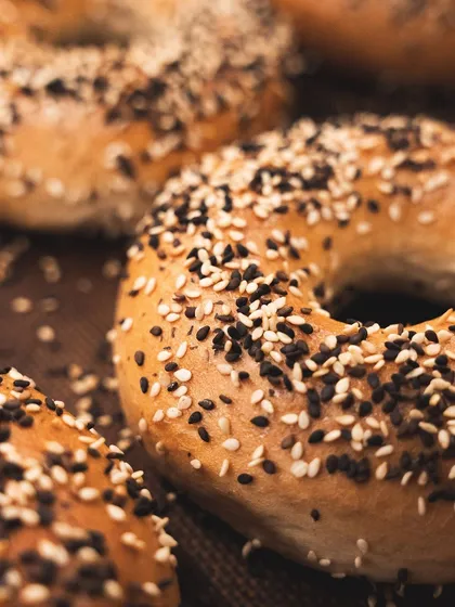 A detailed shot of an everything bagel, showing the generous coating of sesame and poppy seeds.