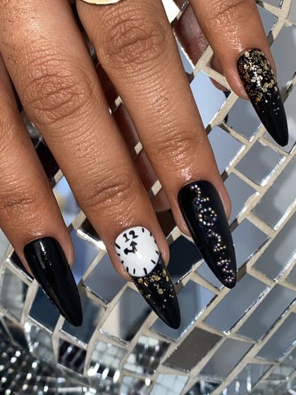 Ring in the New Year with these dramatic stiletto nails. The design features black polish, gold foil, and a hand-painted clock striking midnight.