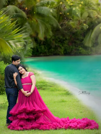 A romantic outdoor portrait of a couple by the water. The vibrant pink gown stands out beautifully against the lush greenery, creating a stunning and memorable image.