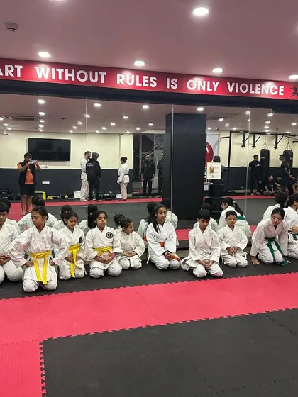 The kids' karate class sits together after their belt test. The mix of belt colors shows the different levels of progress within our supportive group.