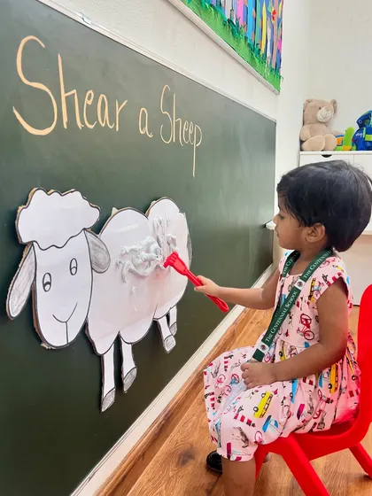 This young learner is completely absorbed in the task of shearing the sheep. We design our activities to be engaging for toddlers, helping them learn through focused play.