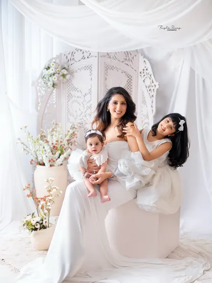 A playful moment between a mother and her two daughters. The all-white theme keeps the image looking clean and focuses on their happy faces.