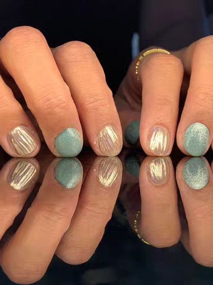 A cool-toned manicure with a mix of mint green, silver cat-eye, and textured silver glitter nails.