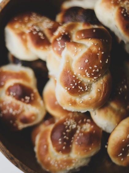 A bowl of freshly baked knotted bread rolls with sesame seeds. Perfect for sharing.
