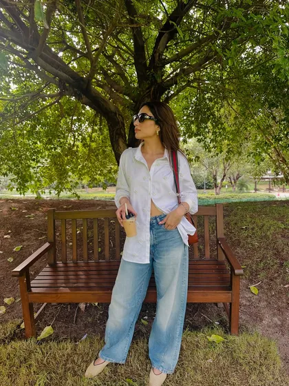 Another look at the oversized shirt and jeans combo, this time in a park setting. It's a timeless look that is both stylish and comfortable.