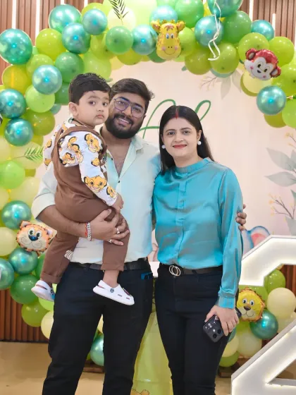 A happy family posing in front of a vibrant jungle-themed balloon arch. My photography style uses bright colors to make your party photos pop.