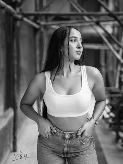The black and white version of a street fashion portrait. Stripping away the color focuses the viewer's attention on the model's expression, the texture of her clothing, and the dramatic lighting.
