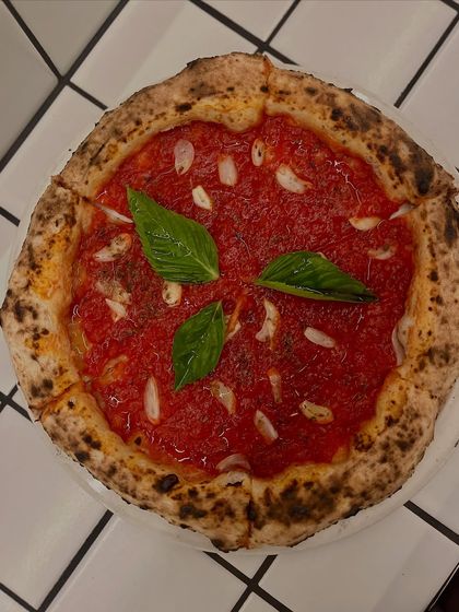 A top-down view of the Marinara pizza, showcasing its vibrant red sauce and fresh basil.