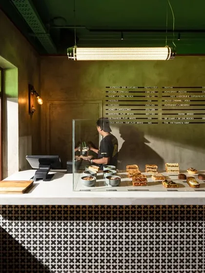 The coffee counter features a bold, graphic tile pattern that contrasts with the rustic, lime-washed walls. This blend of patterns and textures is central to my retro-modern approach, creating visual interest and a unique brand identity for the space.