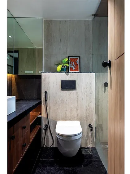 After: Another bathroom transformation, this time with a moodier palette of dark stone and wood. The full-wall mirror visually expands the space.