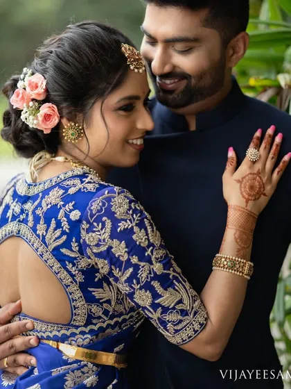 A romantic shot of a couple, with the bride wearing a royal blue saree and a custom blouse with a beautifully embroidered open back.