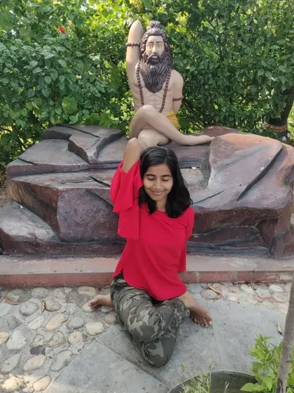A playful attempt at Gomukhasana (Cow Face Pose) next to a statue. Yoga doesn't always have to be serious!