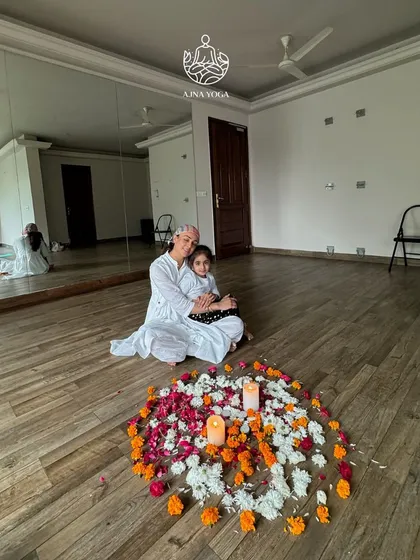 Sitting with my daughter in our studio, surrounded by a mandala of fresh flowers. My journey as a mother is what inspires my work with children, reminding me of the importance of nurturing their pure, creative spirits.