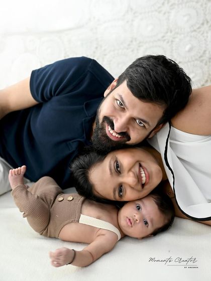 A fun and intimate family close-up. This overhead shot captures the happy faces of the parents and their wide-eyed newborn, creating a playful and loving memory.