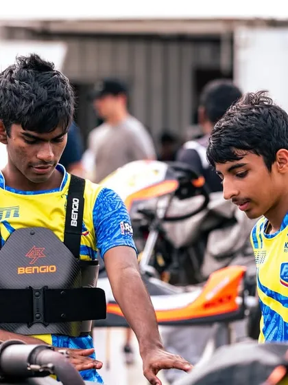 Two of our young drivers inspecting a kart with a mechanic, learning the technical aspects of the sport.