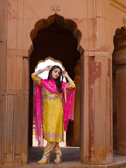 A classic pose that highlights the silhouette of the salwar kameez. The framing within the stone doorway adds depth and a sense of timelessness to this ethnic fashion shot.