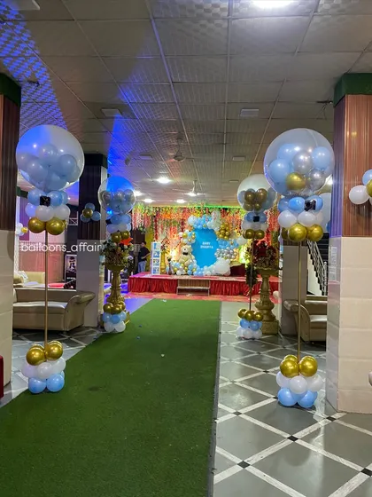 The entrance walkway for a baby's party, lined with balloon pillars topped with large transparent balloons, creating a grand welcome for guests.