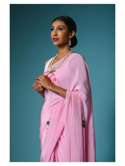 A slightly different pose in the same pink saree, highlighting the pearl accessories and the elegant drape over the shoulder.