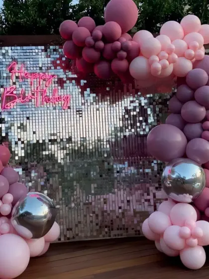 A sophisticated birthday setup with a silver sequin wall. The balloon arrangement in shades of mauve and pink, with large silver disco balls, creates a very chic and modern vibe.