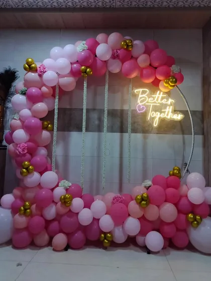 A beautiful 'Better Together' ring backdrop for an intimate celebration. The ring is decorated with an arch of pink and gold balloons and a warm neon sign.