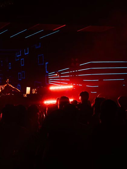 From the stage, looking out at a sea of people moving to the music. This is the view that fuels me, with the red and blue lights painting a picture of pure energy.