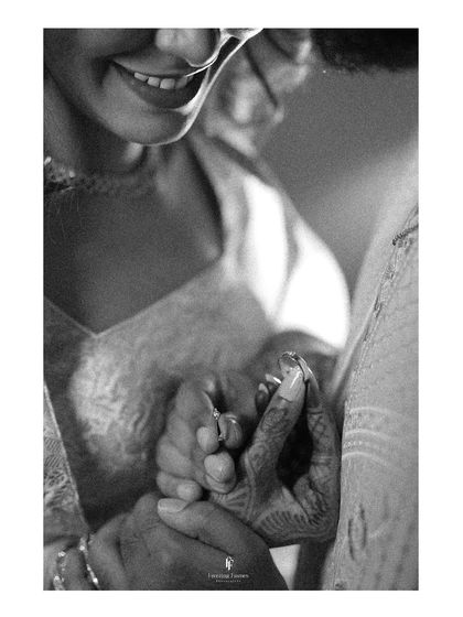 A black and white close-up focusing on the couple's hands and the bride's joyful smile. This artistic shot highlights the intimacy and happiness of the moment.