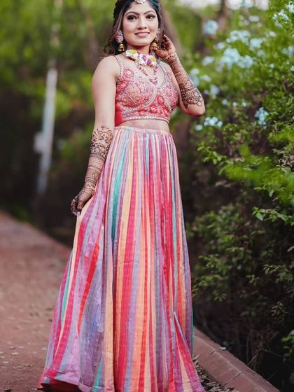 A full-length shot of a bride in a colorful lehenga, her mehandi completing her vibrant look.
