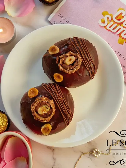 My Ferrero Crunch Doughnut is pure indulgence. It's a baked ring doughnut topped with rich chocolate ganache, roasted hazelnuts, a Nutella drizzle, and a whole Ferrero Rocher.