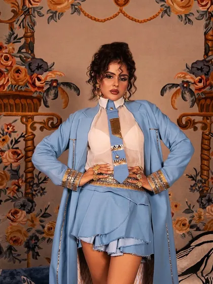A powerful, direct-to-camera shot showcasing the sharp makeup and curly updo created for this high-fashion look.