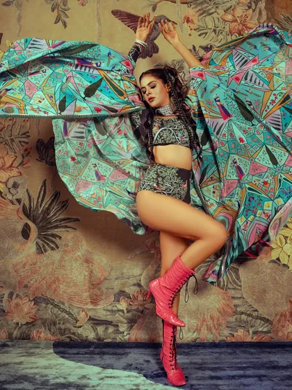 This dynamic shot from a celebrity editorial with Priyanka Chahar Choudhary showcases a bold, high-fashion look. The makeup was designed to stand out against the vibrant, patterned styling, featuring defined eyes and glowing skin that work with the powerful pose and intricate hairstyle.