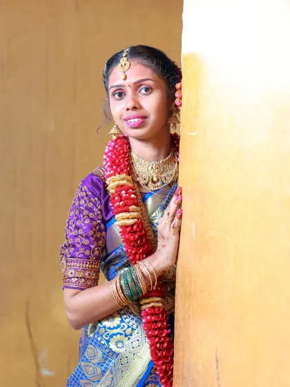 A playful and sweet portrait from a puberty ceremony. Peeking out from behind a wall, her bright smile and traditional jewelry create a charming and memorable image.