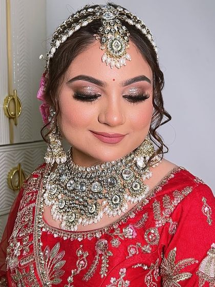 A moment of calm before the ceremony. The glitter on her eyes catches the light beautifully, adding a touch of magic to her classic red bridal look.