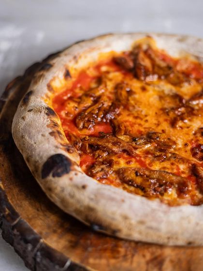 Pizza mania. A rustic, delicious-looking pizza with a rich meat sauce, fresh from the wood-fired oven.