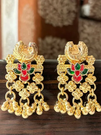 Elegant gold-plated fusion earrings with a traditional touch. These feature a peacock motif with red and green enamel work, finished with delicate dangling gold beads for subtle movement.