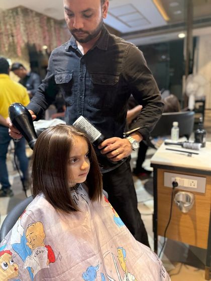 A young client getting a sleek bob haircut. Our stylist is carefully blow-drying her hair, showing the gentle and professional approach we take with our 'Kool Kid' clients.