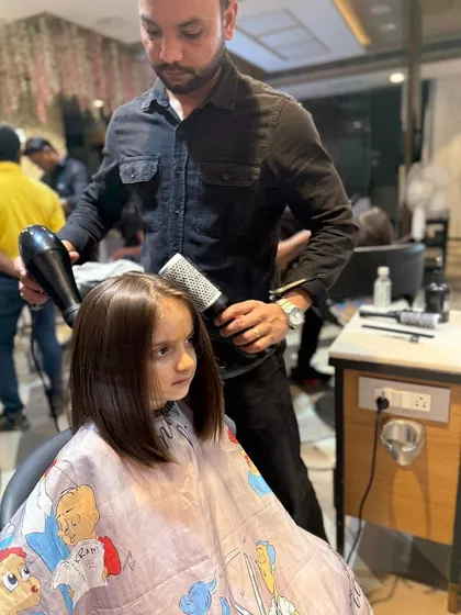 A young client getting a sleek bob haircut. Our stylist is carefully blow-drying her hair, showing the gentle and professional approach we take with our 'Kool Kid' clients.
