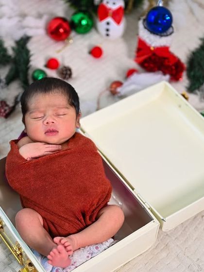 A festive Christmas theme with the newborn nestled in a gift box. This is a creative way to announce the best gift of all.