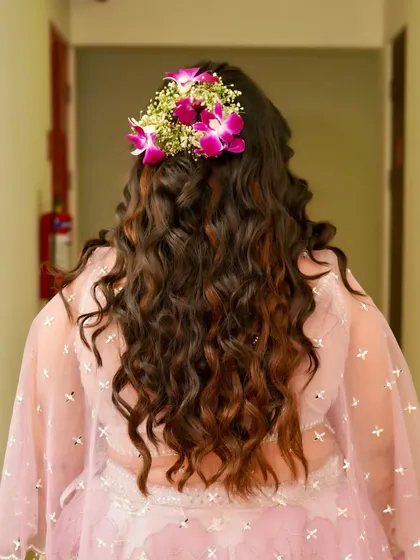 Another view of the Haldi hairstyle, showing a beautiful floral crown made of fresh orchids and baby's breath. This is a popular choice for pre-wedding events.