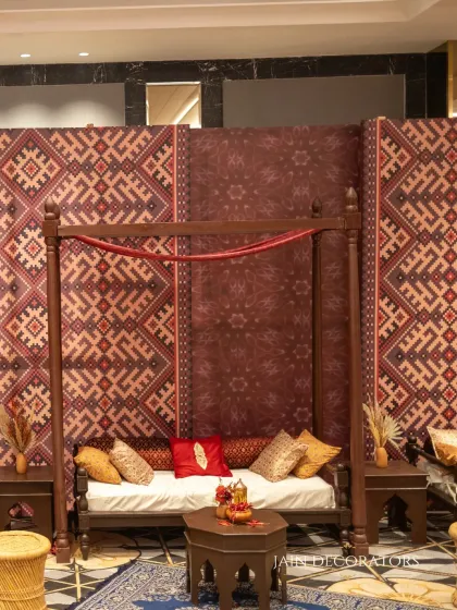 A cozy seating area with a touch of tradition. The wooden daybed is set against a backdrop of patola-print fabric, creating a comfortable and stylish nook for guests.