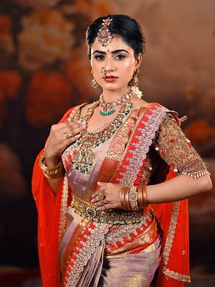 A classic three-quarter portrait of a bride against a painted floral backdrop. This composition is perfect for showcasing the full splendor of the bridal lehenga and jewelry.