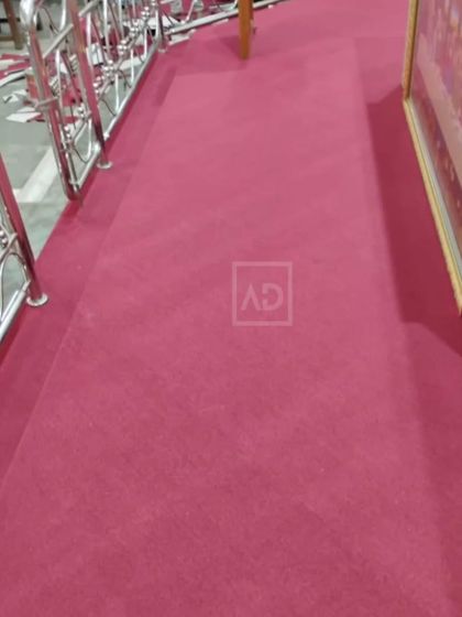 This magenta carpet was installed in a large hall, running alongside a stainless steel railing. The color adds a sense of occasion to the space.