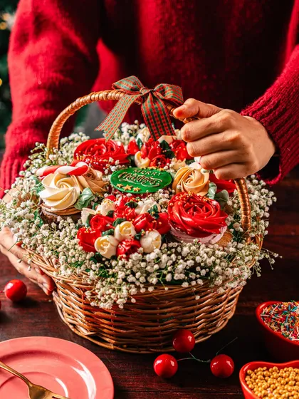 Another angle of the Christmas cupcake bouquet, held to show its generous size and intricate presentation. It's a perfect Secret Santa gift or a centerpiece for a family gathering.