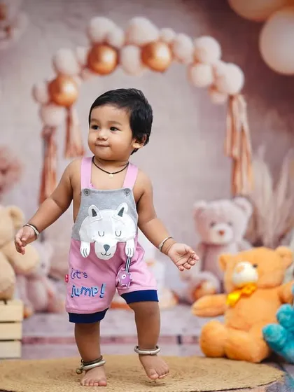 Before the cake smash, we capture some adorable portraits of the birthday boy in his cute outfit, surrounded by teddy bears.