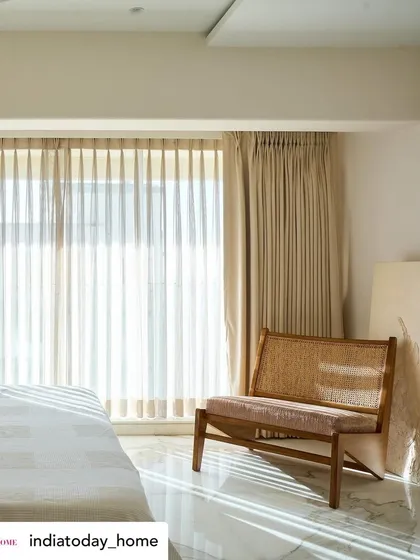 A sunlit corner in the 'House on the Hill' bedroom, as seen in India Today Home. The natural light filtering through the sheer curtains highlights the texture of the rattan and wood chair, creating a peaceful moment.