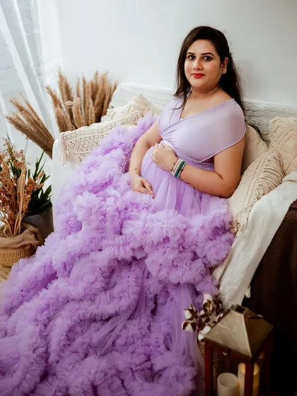 Our studio wardrobe features stunning pieces like this lavender ruffled gown that adds so much drama and elegance. We styled this shot in our Jayanagar studio with a boho-chic setup to create a warm, inviting atmosphere for this beautiful mom-to-be.
