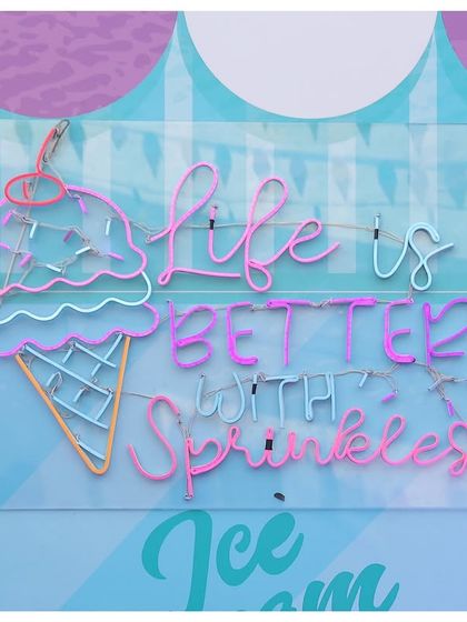 A custom neon sign that reads 'Life is better with sprinkles', perfectly capturing the fun and whimsical spirit of the ice cream theme.