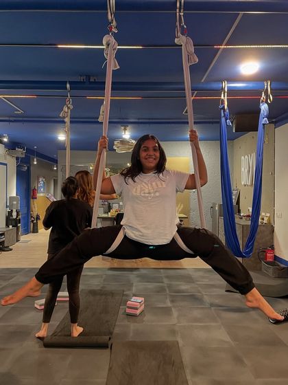 Achieving a full split in the hammock with a huge smile. This is a perfect example of celebrating a personal win within our supportive group.
