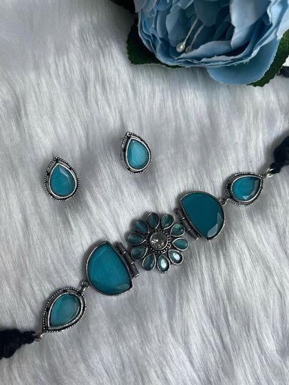 A beautiful black polish silver replica choker with sky blue stones. This set includes the choker and matching teardrop studs.