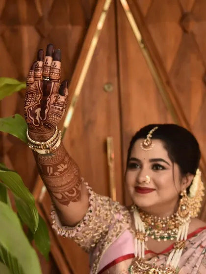 A happy client waving and showing off the detailed portrait work on her palm. The rich stain and intricate design are on full display, adding to her festive baby shower look.