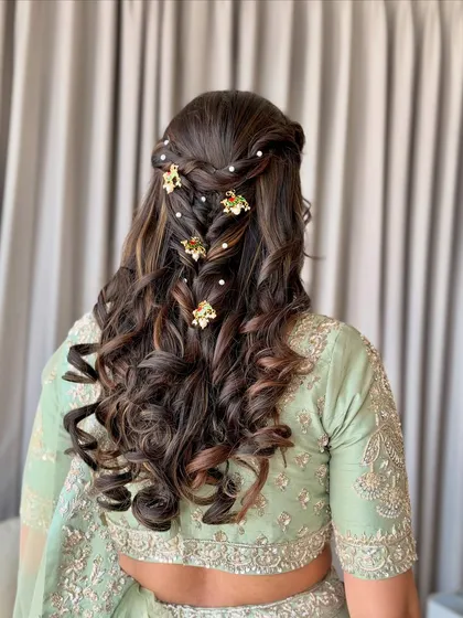 A beautiful braided half-updo with soft waves, decorated with golden floral clips and pearls.